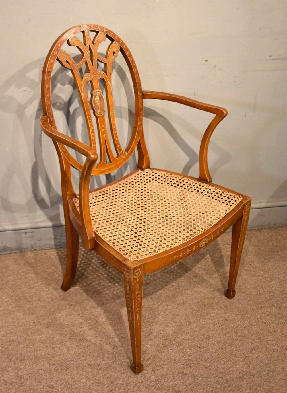 An Edwardian satinwood open armchair featuring an oval pierced backrest, hand-painted floral motifs, sweeping arms, and a woven cane seat. View VI