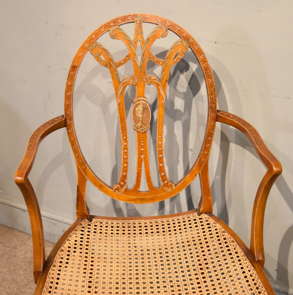An Edwardian satinwood open armchair featuring an oval pierced backrest, hand-painted floral motifs, sweeping arms, and a woven cane seat. View VII