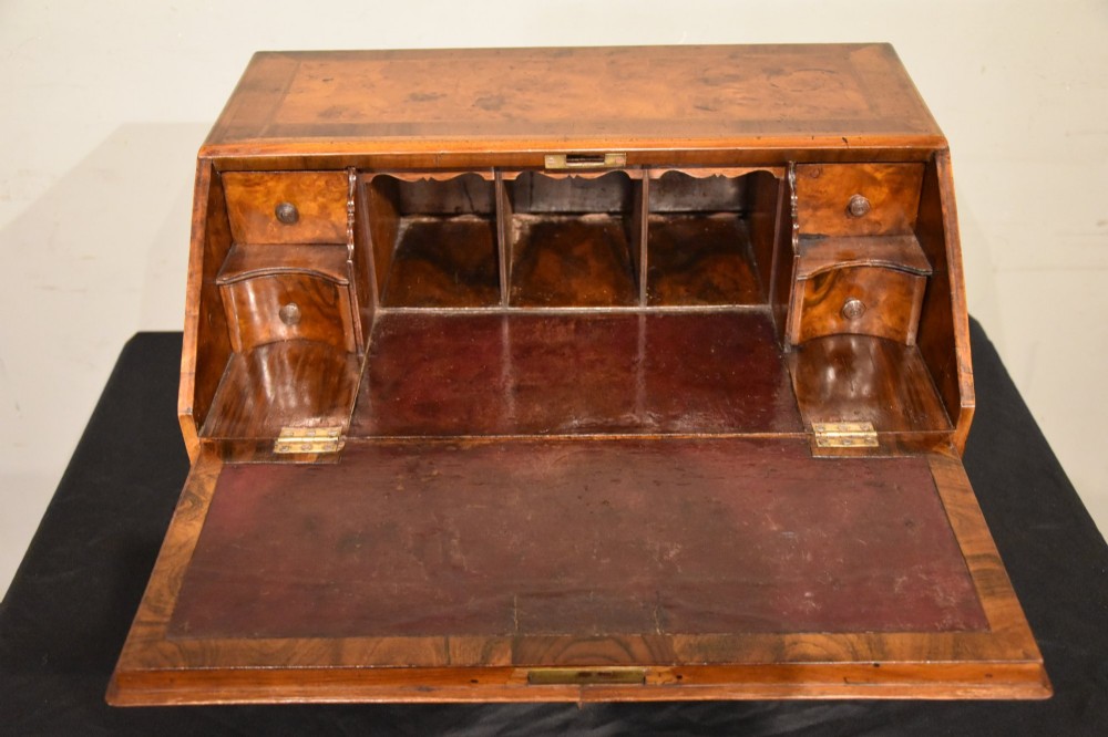 A George I period burr walnut travelling writing bureau with a sloped fall-front lid, lower drawer, and brass escutcheons. View III