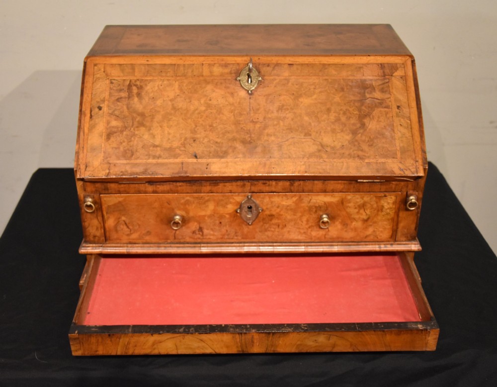 A George I period burr walnut travelling writing bureau with a sloped fall-front lid, lower drawer, and brass escutcheons. View IV