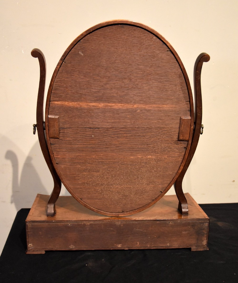A Georgian mahogany dressing mirror featuring an oval adjustable mirror supported by curved uprights above a serpentine-fronted base with three small drawers. View VI