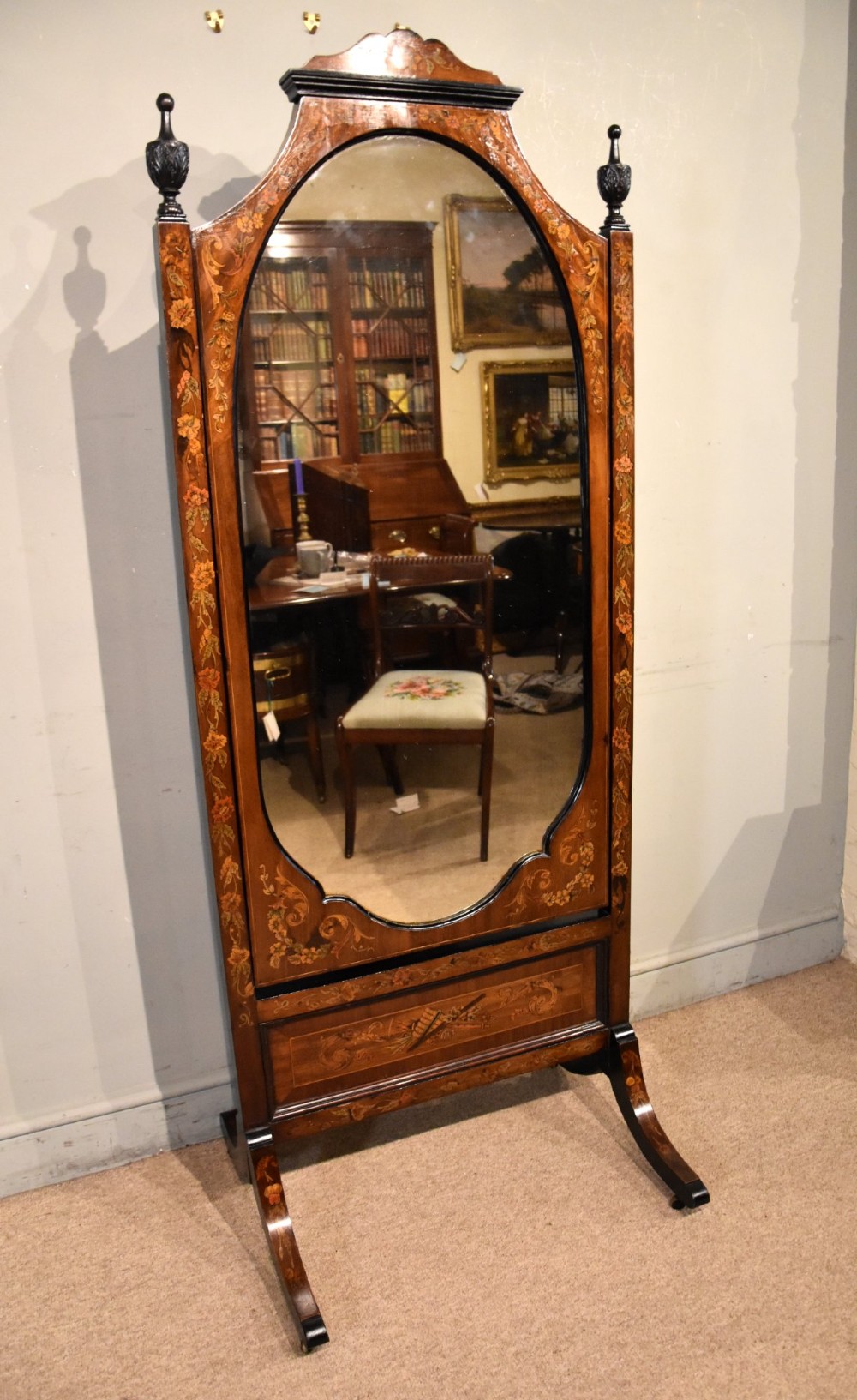 A Victorian mahogany cheval mirror featuring detailed floral marquetry inlays, carved urn finials, an arched glass frame, and splayed feet. View III