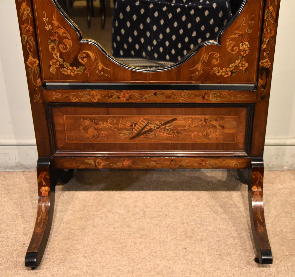 A Victorian mahogany cheval mirror featuring detailed floral marquetry inlays, carved urn finials, an arched glass frame, and splayed feet. View V
