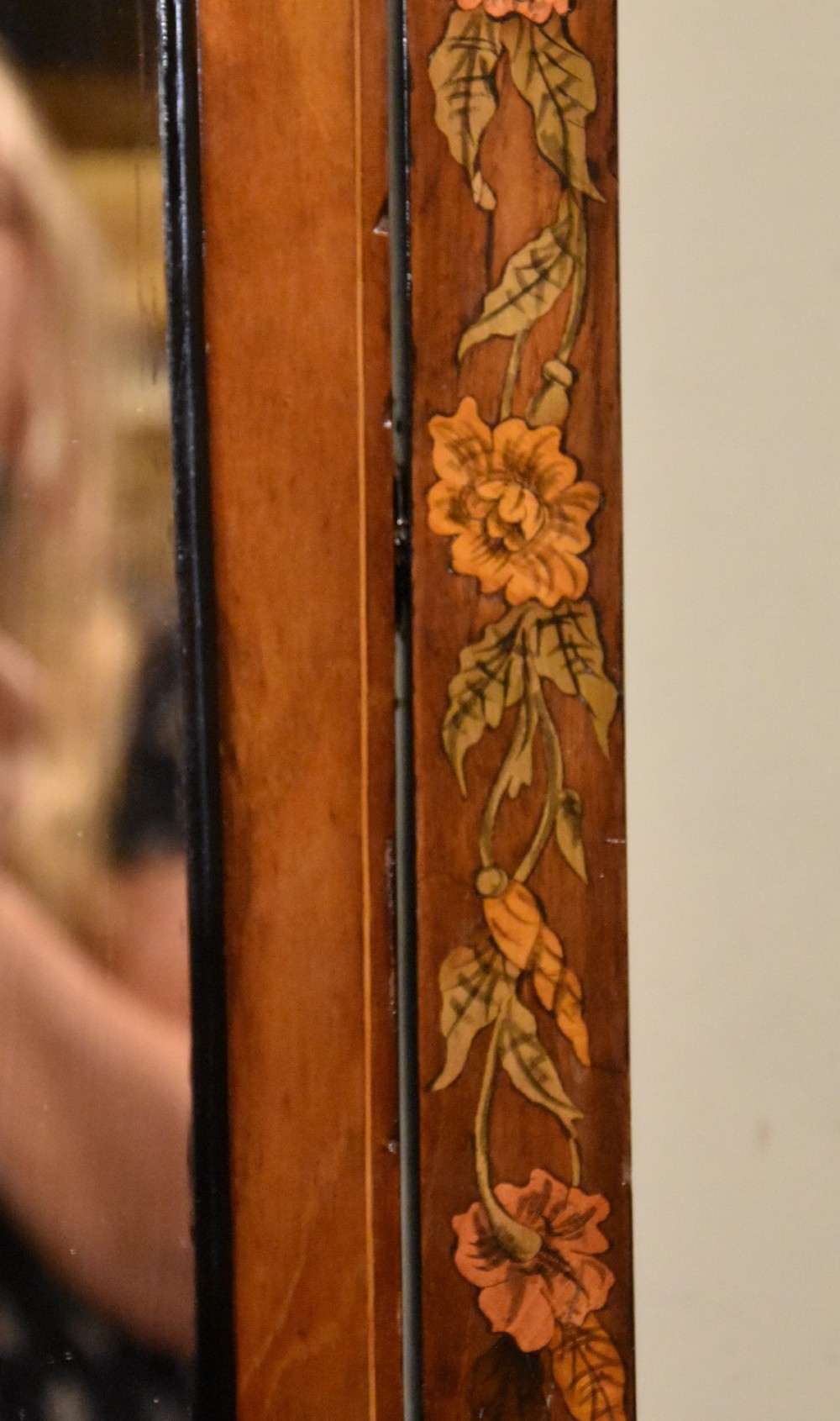 A Victorian mahogany cheval mirror featuring detailed floral marquetry inlays, carved urn finials, an arched glass frame, and splayed feet. View VII