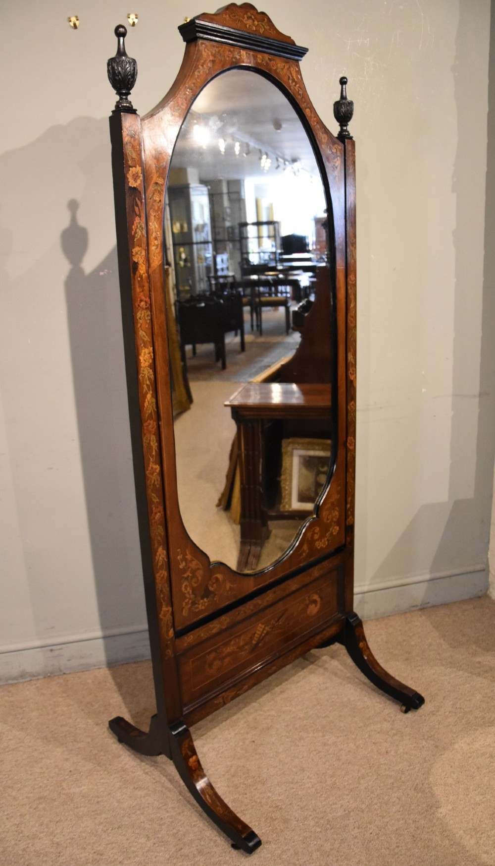 A Victorian mahogany cheval mirror featuring detailed floral marquetry inlays, carved urn finials, an arched glass frame, and splayed feet. View VIII