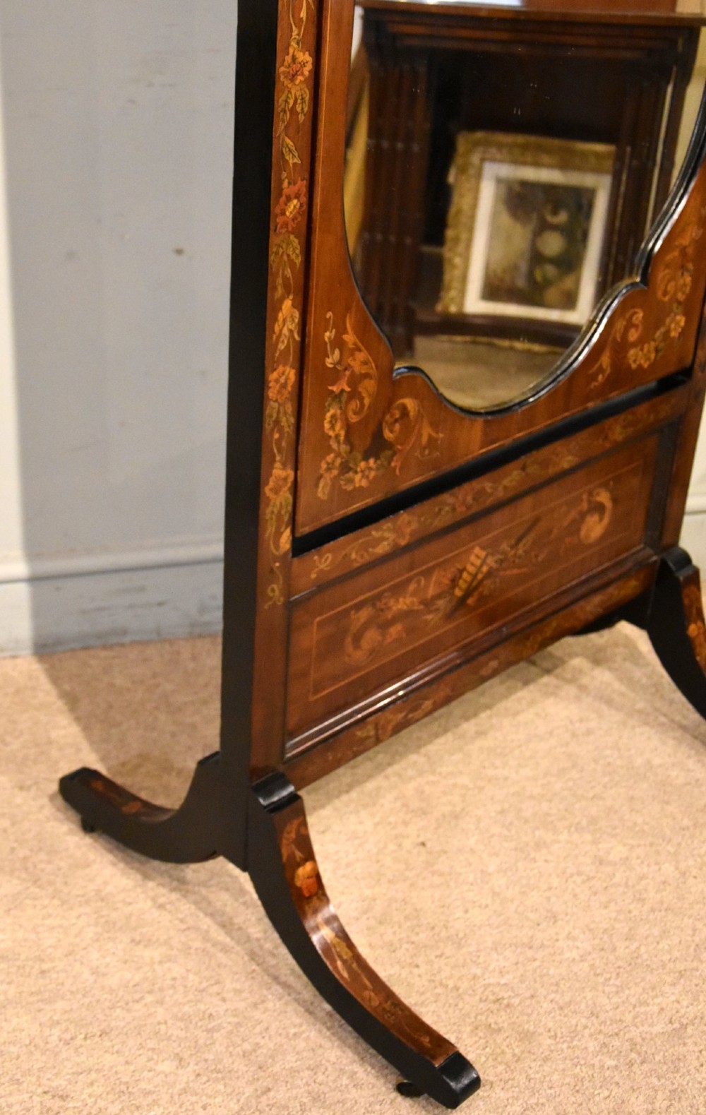 A Victorian mahogany cheval mirror featuring detailed floral marquetry inlays, carved urn finials, an arched glass frame, and splayed feet. View IX