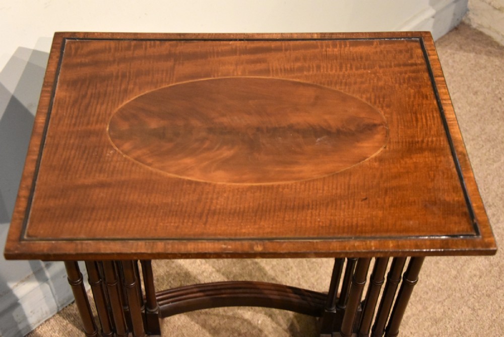 A set of four graduated Edwardian mahogany nest tables displayed in a stepped formation, featuring turned legs and an oval inlaid top. View III