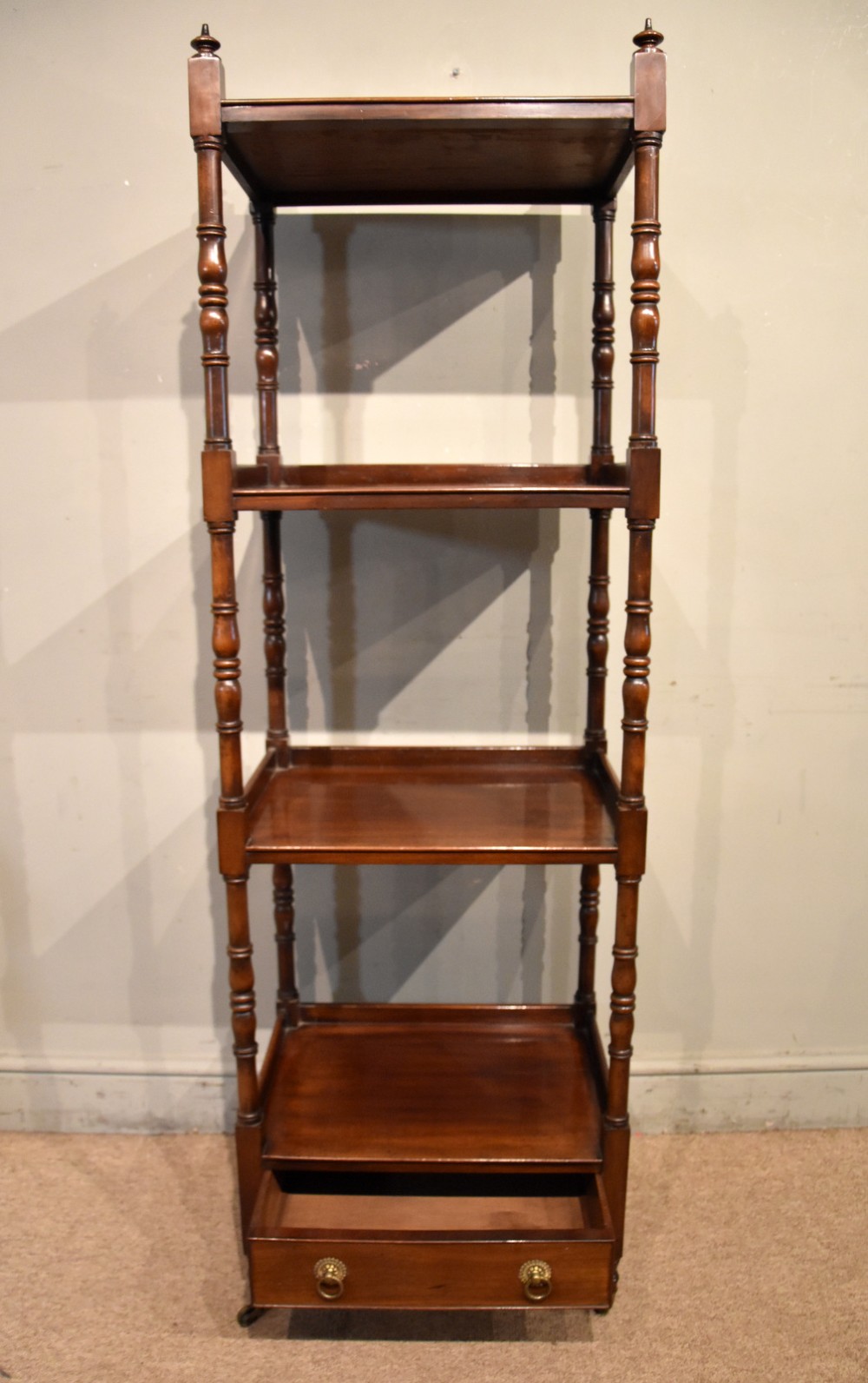A late nineteenth-century mahogany four-tier whatnot featuring turned spindle supports, a lower drawer with brass ring handles, and brass casters. View III