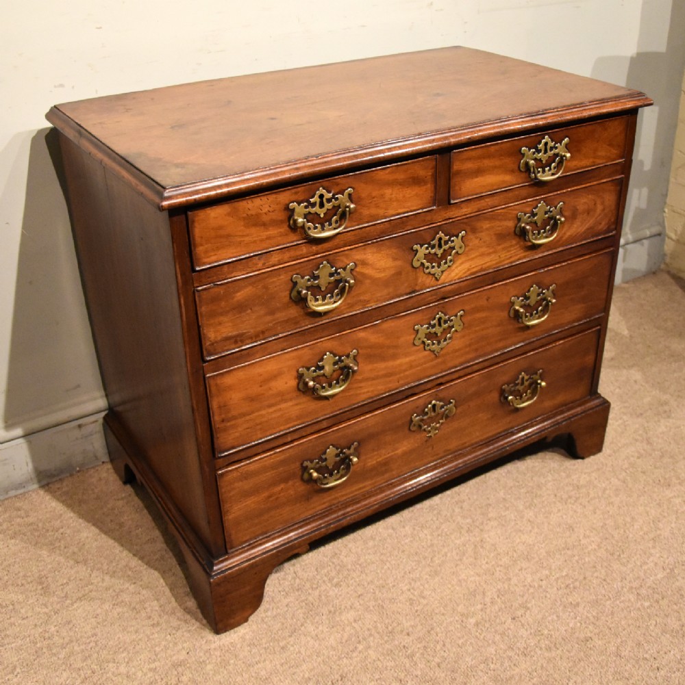 A small George III mahogany chest of drawers featuring pierced brass backplates, swan-neck handles, and bracket feet.