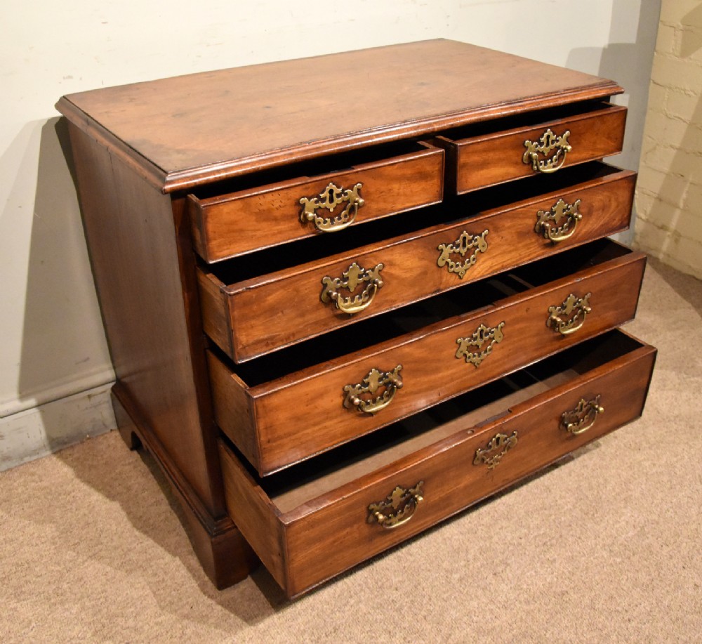 A small George III mahogany chest of drawers featuring pierced brass backplates, swan-neck handles, and bracket feet. View II