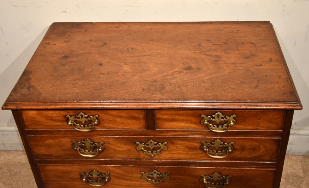 A small George III mahogany chest of drawers featuring pierced brass backplates, swan-neck handles, and bracket feet. View III