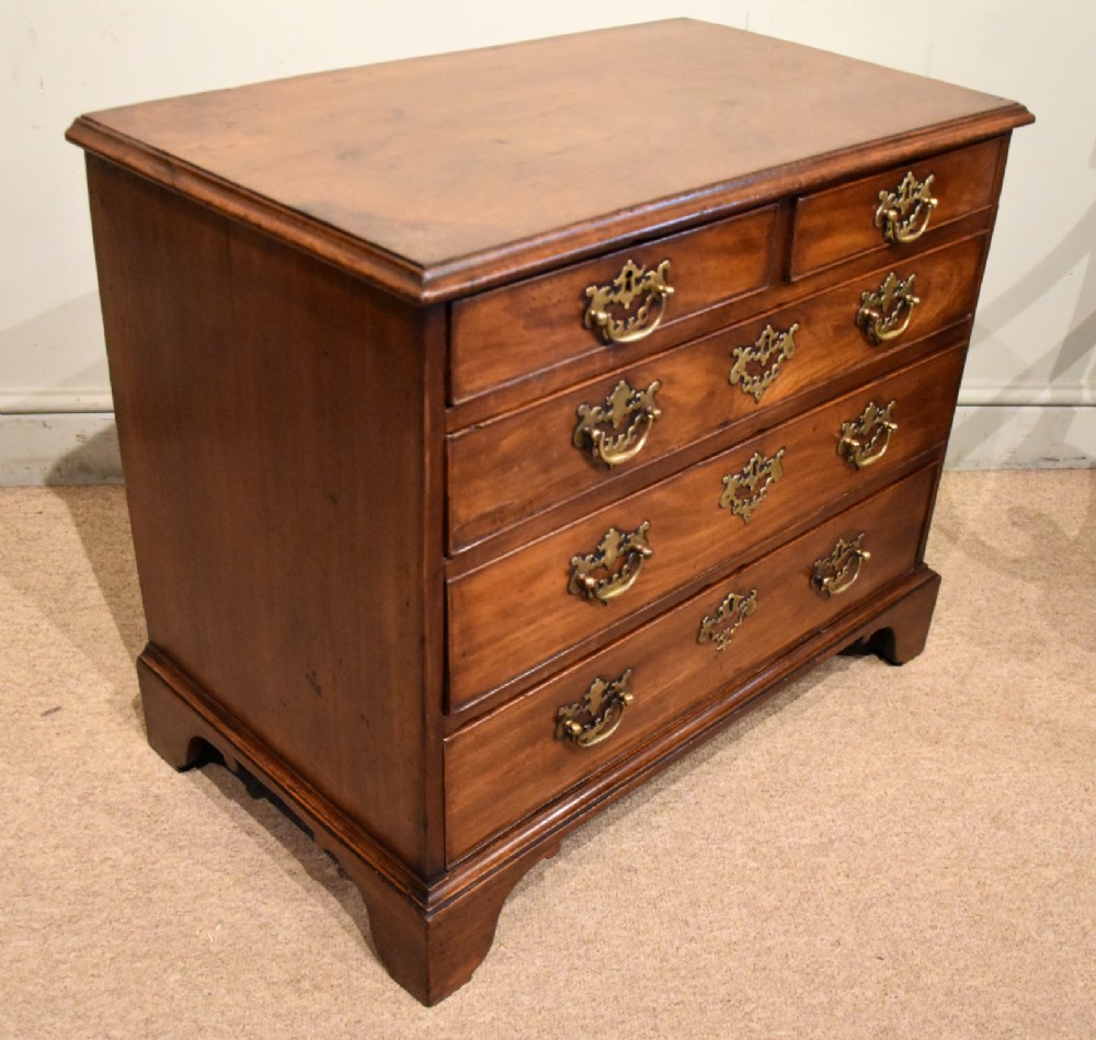 A small George III mahogany chest of drawers featuring pierced brass backplates, swan-neck handles, and bracket feet. View IV