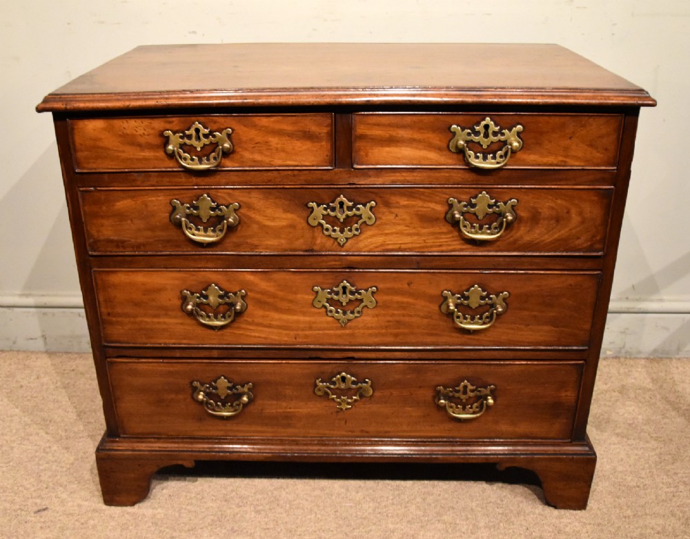 A small George III mahogany chest of drawers featuring pierced brass backplates, swan-neck handles, and bracket feet. View V