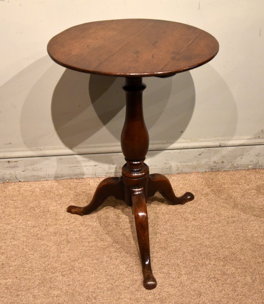 A small Georgian mahogany tripod wine table featuring a circular top, turned central baluster pedestal, and three cabriole legs with pad feet.