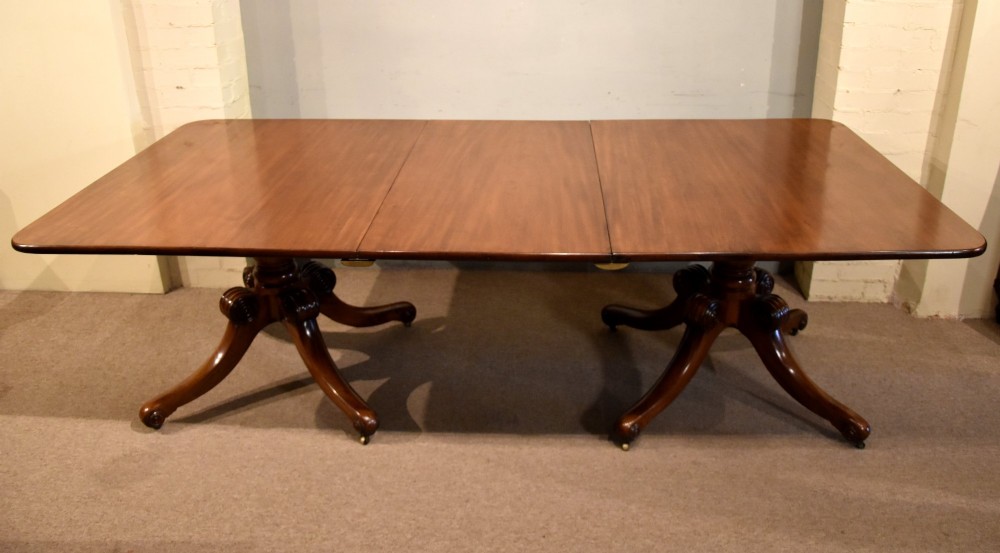A Regency period mahogany extending dining table supported by two turned pedestal bases with reeded splayed legs and brass castors.