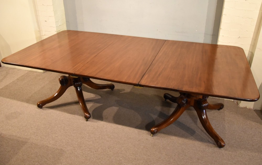 A Regency period mahogany extending dining table supported by two turned pedestal bases with reeded splayed legs and brass castors. View III