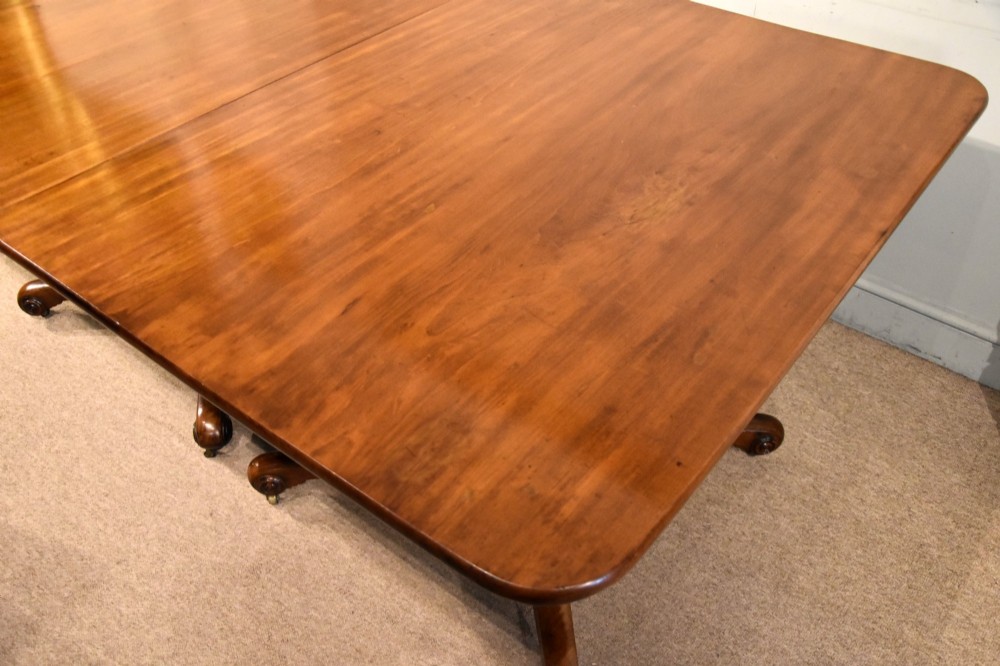 A Regency period mahogany extending dining table supported by two turned pedestal bases with reeded splayed legs and brass castors. View V