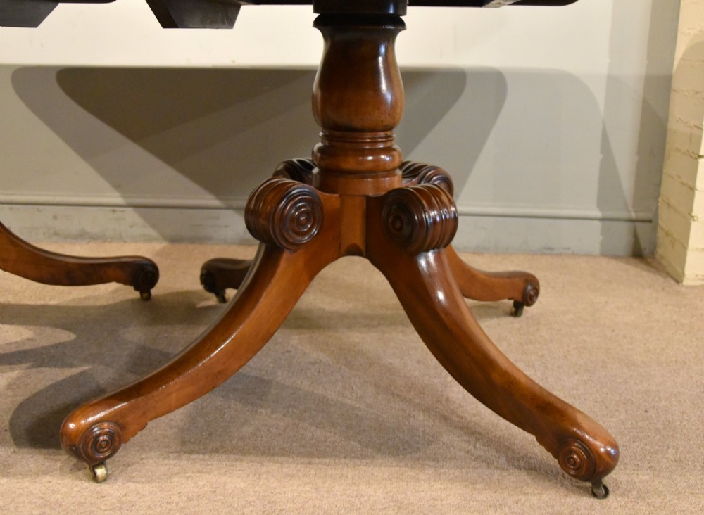A Regency period mahogany extending dining table supported by two turned pedestal bases with reeded splayed legs and brass castors. View VI