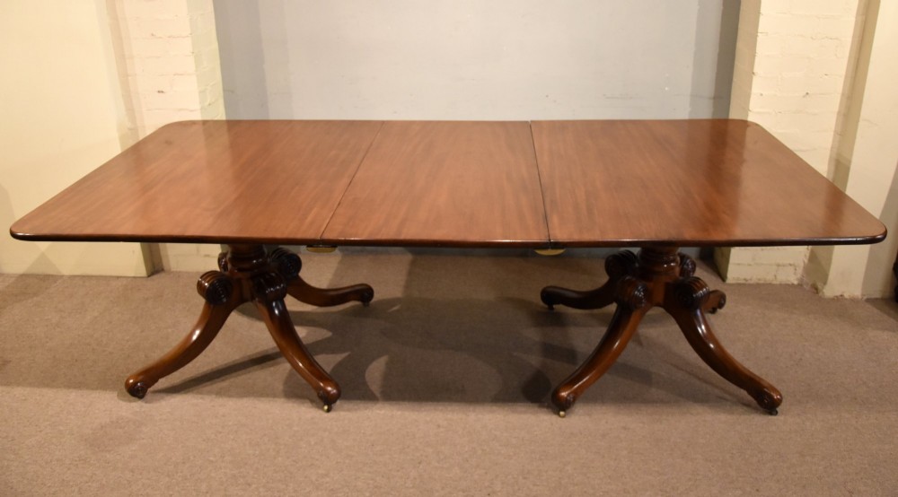 A Regency period mahogany extending dining table supported by two turned pedestal bases with reeded splayed legs and brass castors. View X