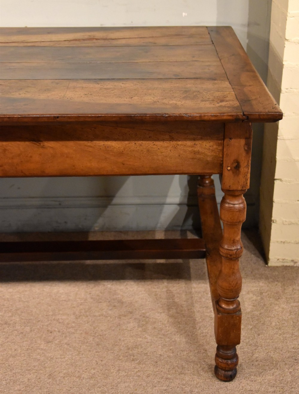 A 19th-century French walnut farmhouse dining table featuring a wide plank top, plain frieze, turned legs, and a low H-stretcher. View III