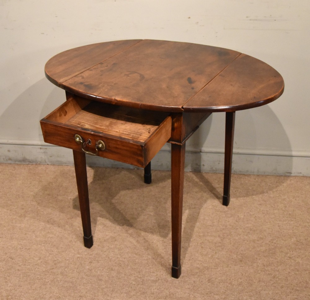 An 18th-century Georgian mahogany Pembroke table featuring an oval drop-leaf top, a frieze drawer with a brass handle, and four square tapered legs. View III