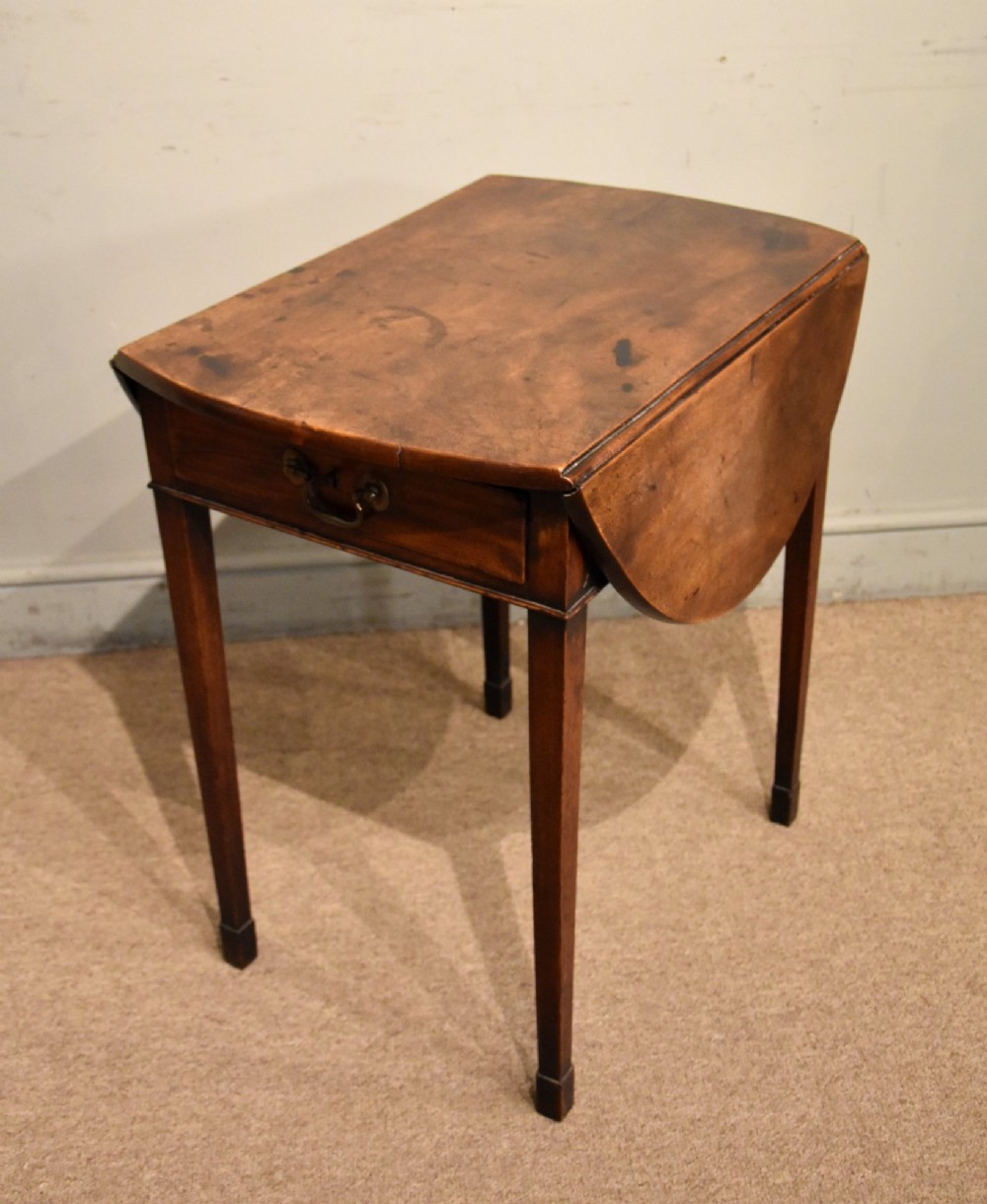 An 18th-century Georgian mahogany Pembroke table featuring an oval drop-leaf top, a frieze drawer with a brass handle, and four square tapered legs. View VI
