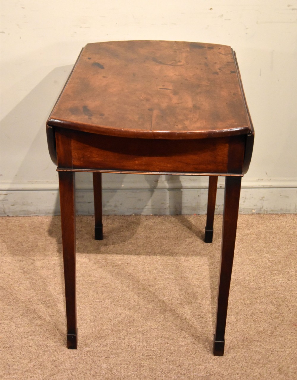 An 18th-century Georgian mahogany Pembroke table featuring an oval drop-leaf top, a frieze drawer with a brass handle, and four square tapered legs. View VIII
