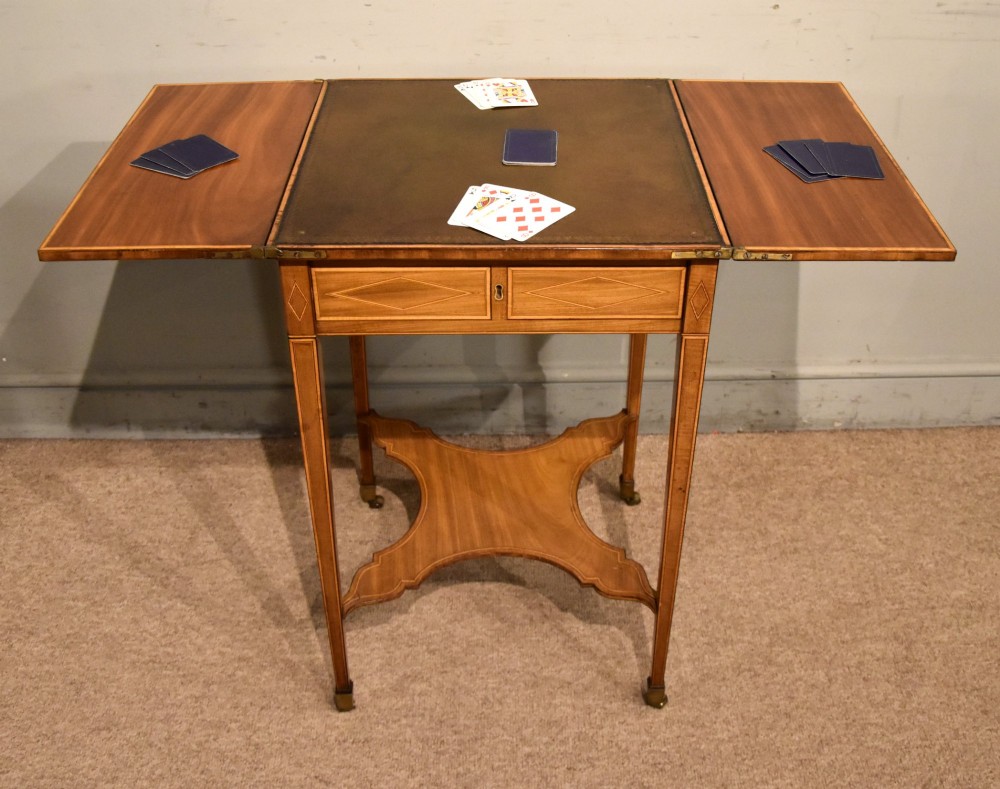 A Sheraton period mahogany writing table featuring folding side leaves, a green leather inset writing surface, diamond marquetry inlay, and a lower shaped stretcher. View II