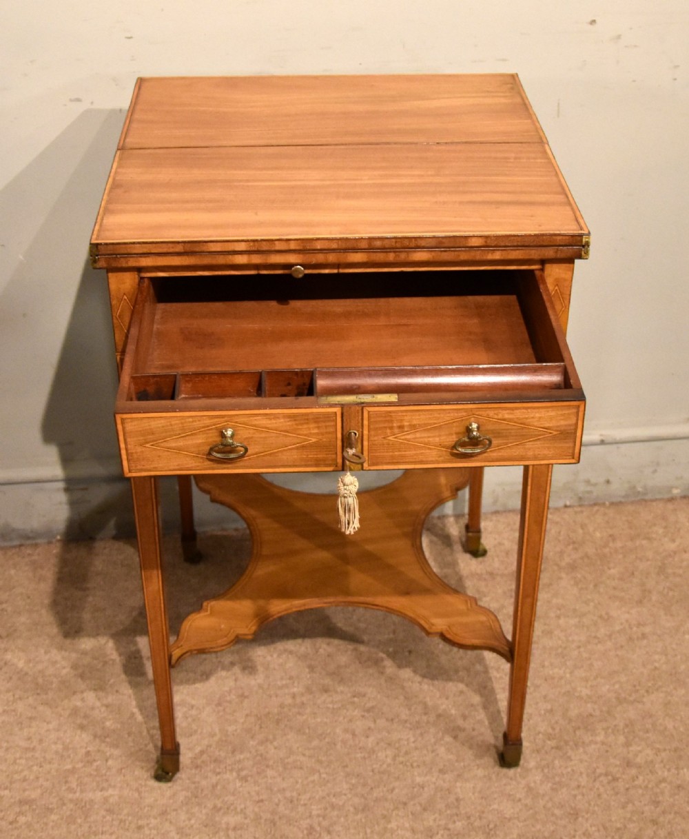 A Sheraton period mahogany writing table featuring folding side leaves, a green leather inset writing surface, diamond marquetry inlay, and a lower shaped stretcher. View IV