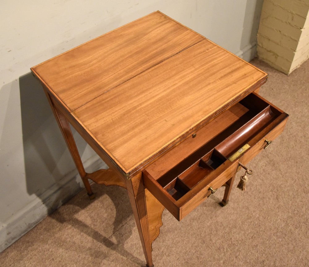 A Sheraton period mahogany writing table featuring folding side leaves, a green leather inset writing surface, diamond marquetry inlay, and a lower shaped stretcher. View V