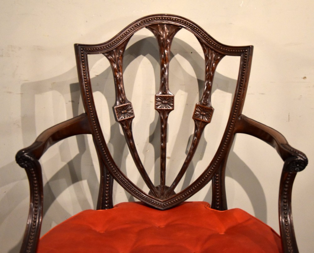 An 18th-century George III carved mahogany armchair featuring a shield-shaped open backrest, swept armrests, and a button-tufted red leather seat cushion. View III