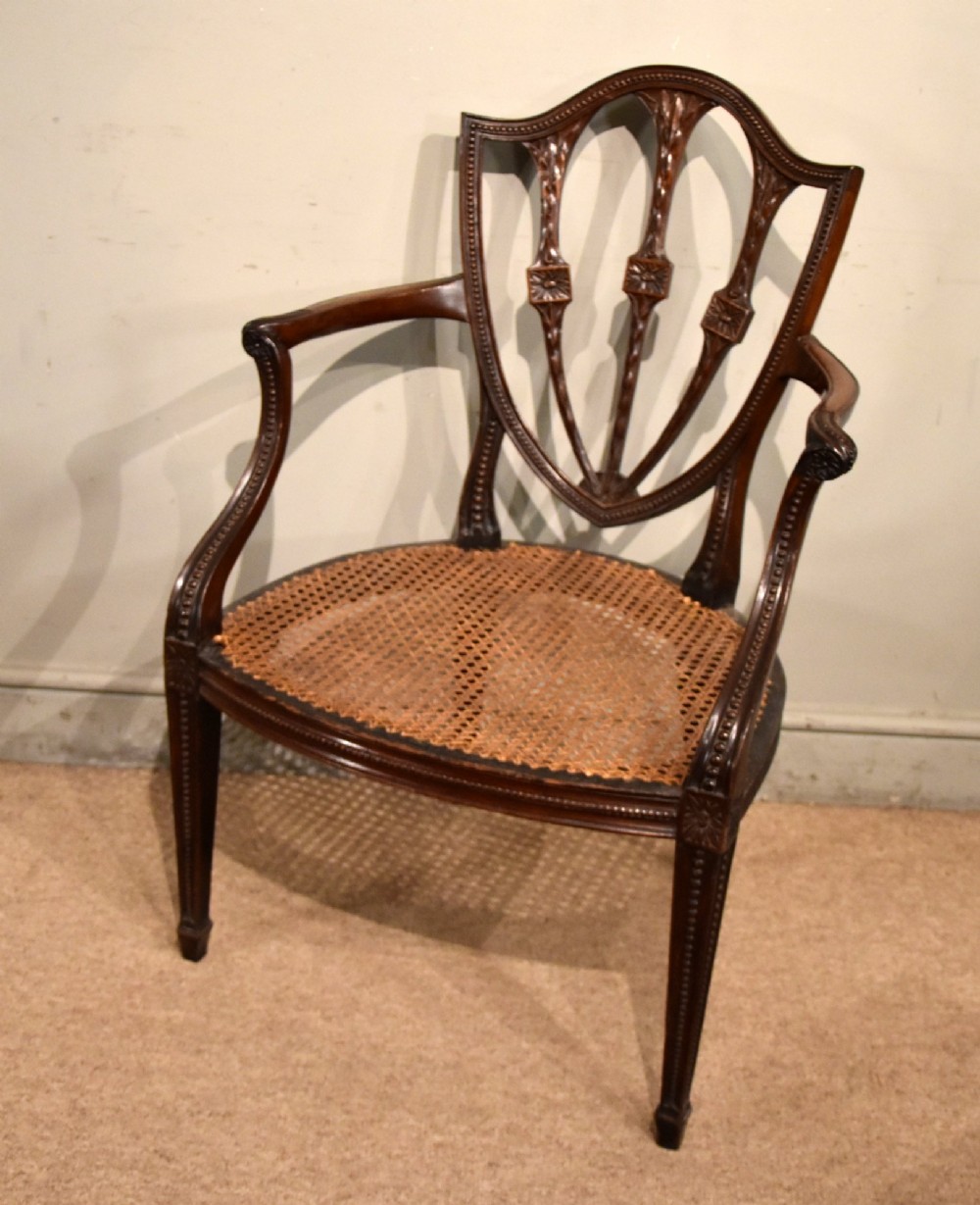 An 18th-century George III carved mahogany armchair featuring a shield-shaped open backrest, swept armrests, and a button-tufted red leather seat cushion. View VI