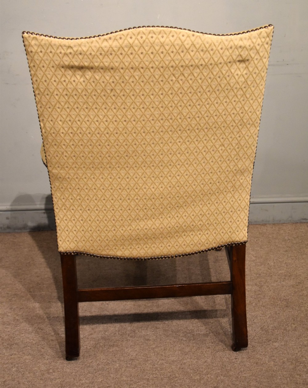 A George III mahogany Gainsborough library armchair upholstered in yellow patterned fabric with scroll arms and brass stud trim. View V