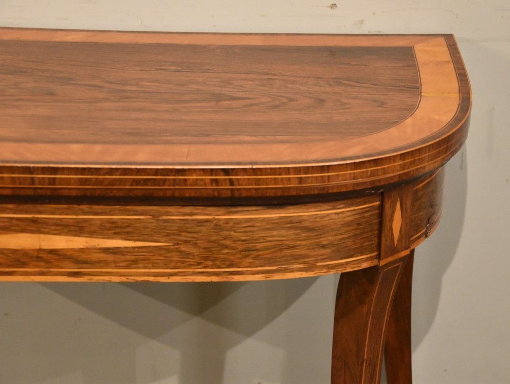 A Regency rosewood foldover card table featuring satinwood crossbanding and an inlaid diamond motif on swept legs. View IV