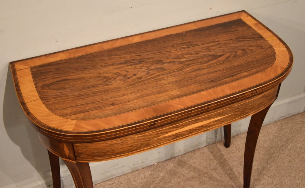 A Regency rosewood foldover card table featuring satinwood crossbanding and an inlaid diamond motif on swept legs. View V