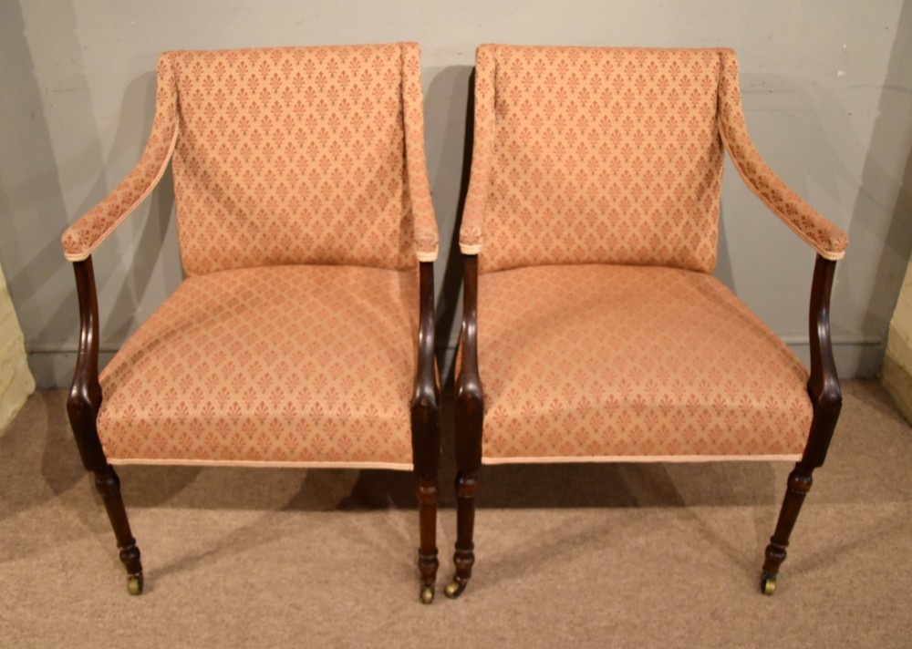 A pair of antique mahogany armchairs featuring terracotta pattern upholstery, sweeping armrests, turned front legs, and brass castors. View II