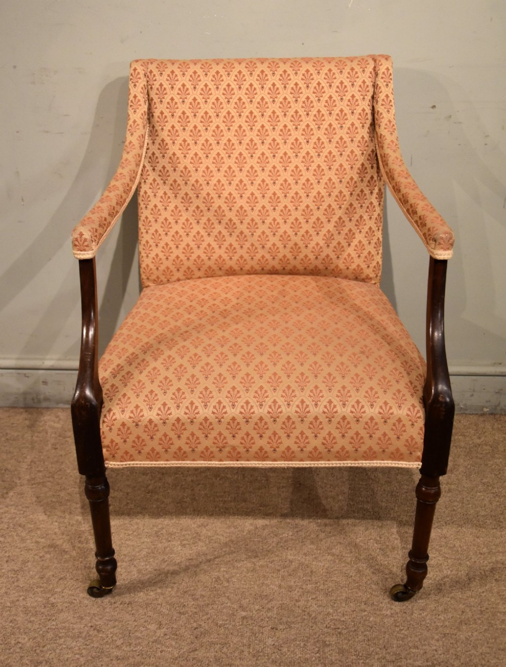 A pair of antique mahogany armchairs featuring terracotta pattern upholstery, sweeping armrests, turned front legs, and brass castors. View III