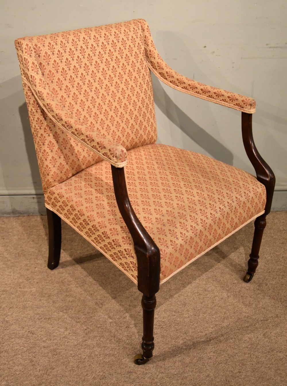 A pair of antique mahogany armchairs featuring terracotta pattern upholstery, sweeping armrests, turned front legs, and brass castors. View IV
