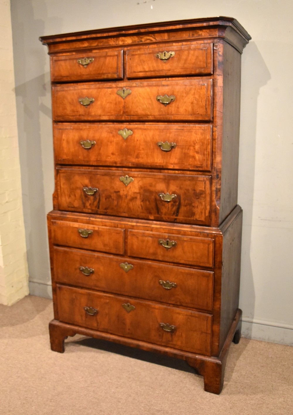 A George III walnut chest on chest featuring two short over three long drawers on the upper section and two short over two long drawers below, set on bracket feet with brass handles. View II