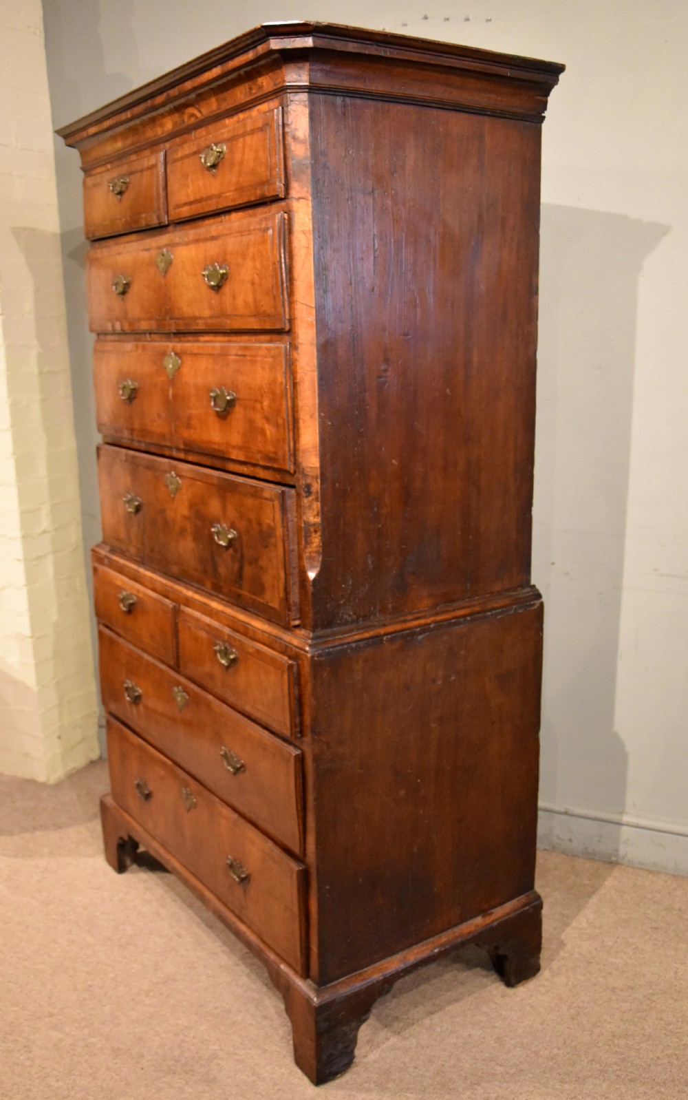 A George III walnut chest on chest featuring two short over three long drawers on the upper section and two short over two long drawers below, set on bracket feet with brass handles. View IV
