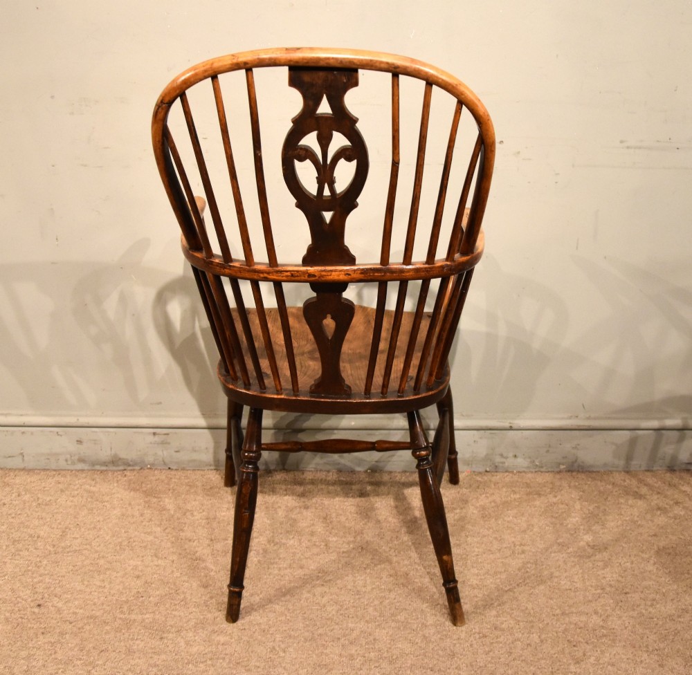 A pair of antique Welsh high-back Windsor armchairs crafted from warm brown elm, featuring pierced splats, spindle backs, shaped seats, and turned legs joined by stretchers. View V
