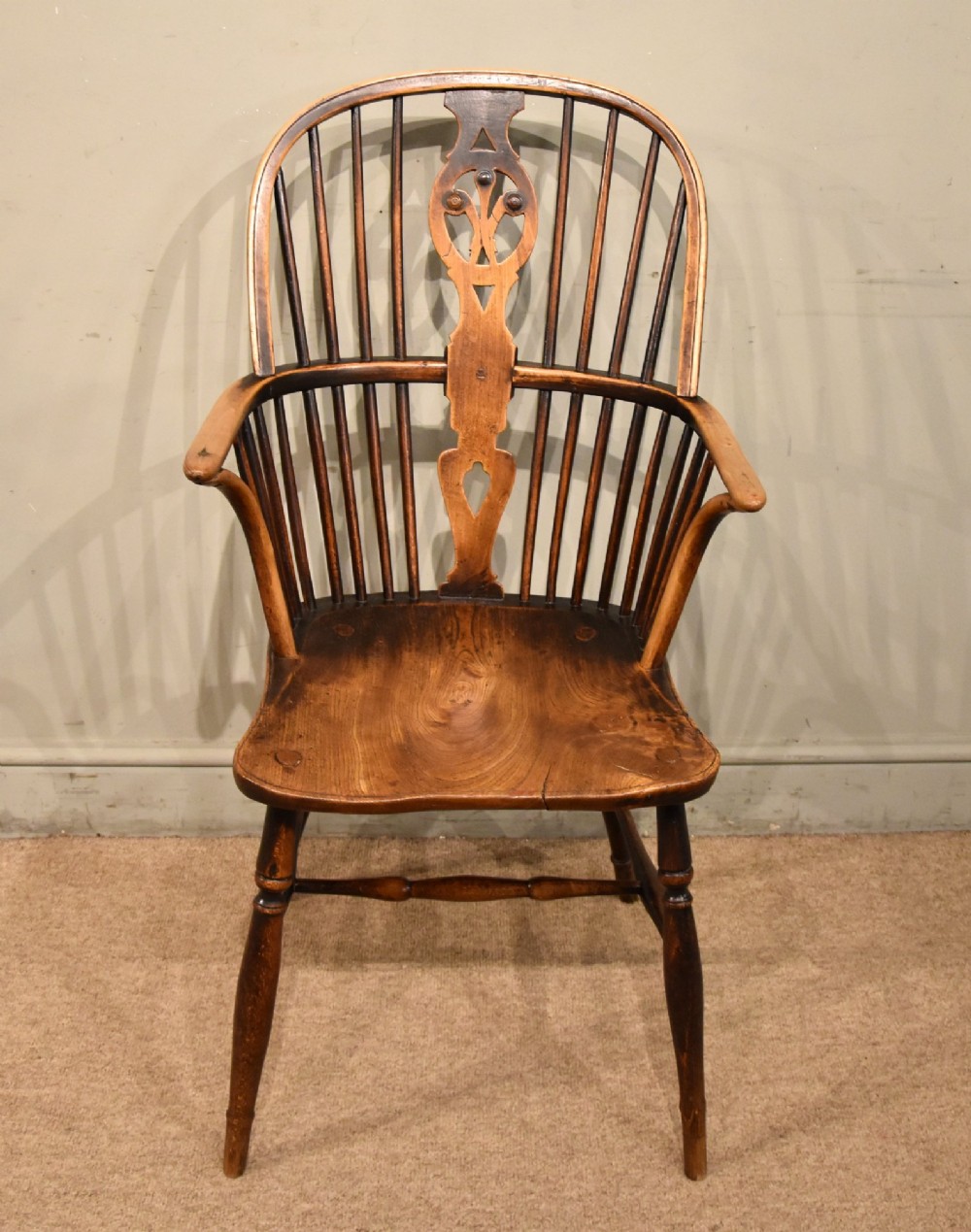 A pair of antique Welsh high-back Windsor armchairs crafted from warm brown elm, featuring pierced splats, spindle backs, shaped seats, and turned legs joined by stretchers. View VIII