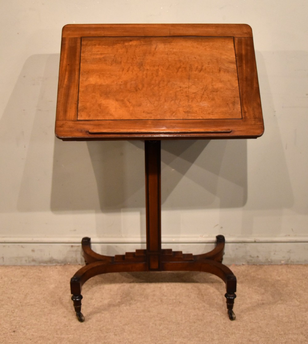 A Regency period mahogany reading stand featuring a rectangular tilting top resting on a central pedestal column with splayed legs and brass castors.