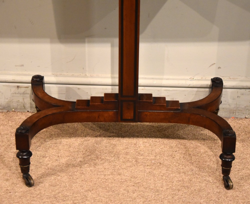 A Regency period mahogany reading stand featuring a rectangular tilting top resting on a central pedestal column with splayed legs and brass castors. View II