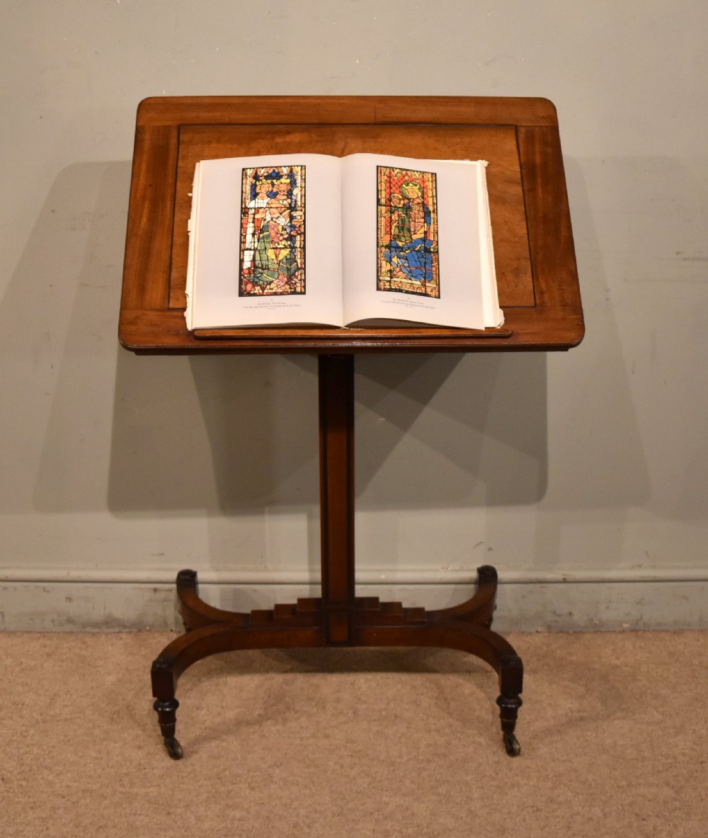 A Regency period mahogany reading stand featuring a rectangular tilting top resting on a central pedestal column with splayed legs and brass castors. View III
