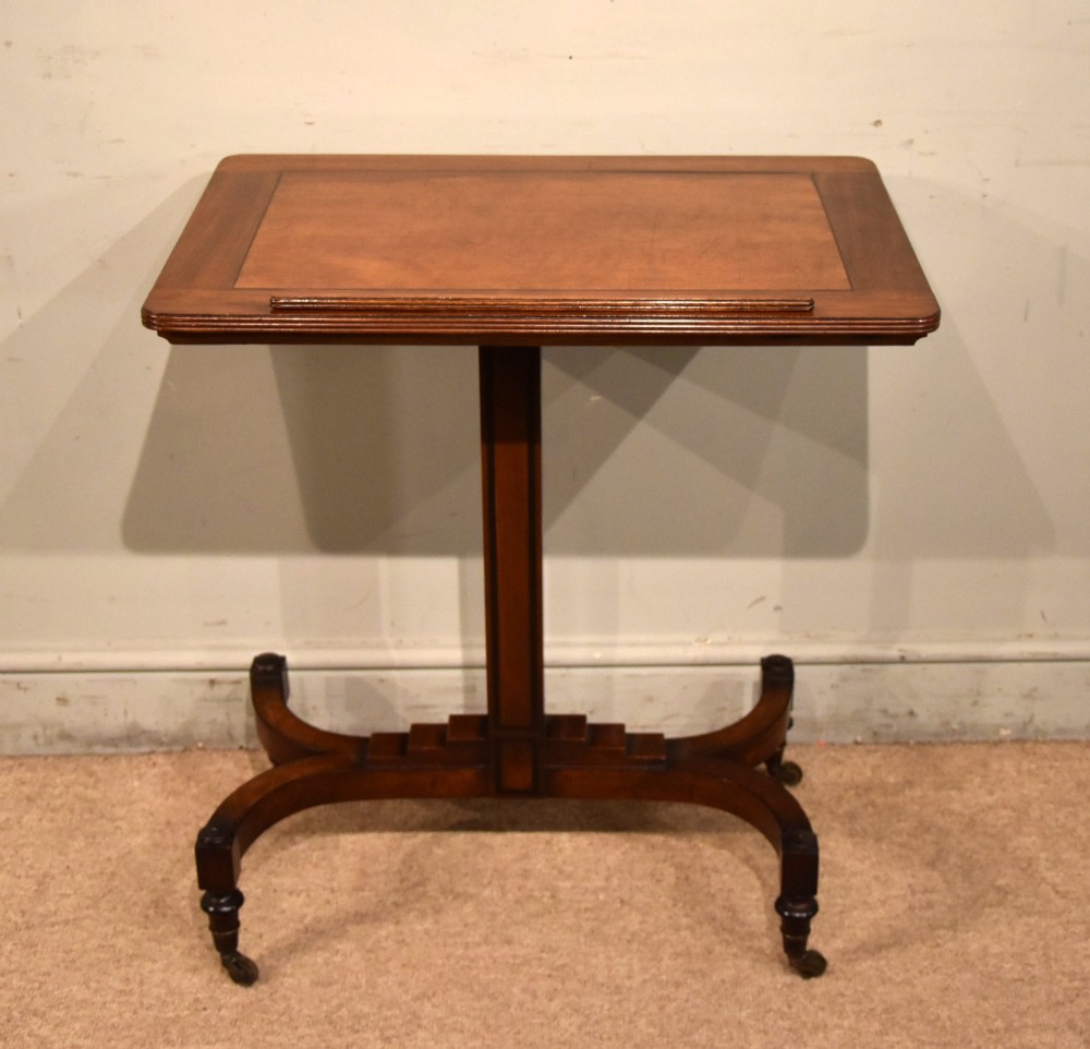 A Regency period mahogany reading stand featuring a rectangular tilting top resting on a central pedestal column with splayed legs and brass castors. View IV