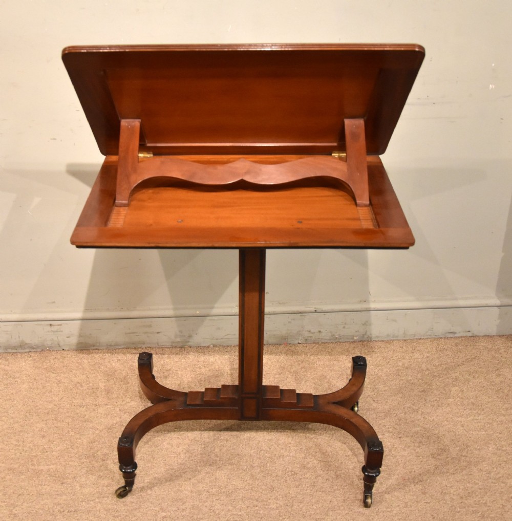 A Regency period mahogany reading stand featuring a rectangular tilting top resting on a central pedestal column with splayed legs and brass castors. View VII
