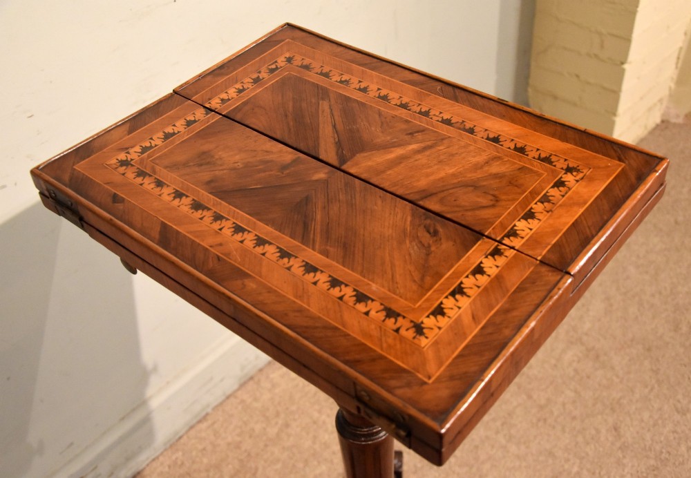 A Regency period patience table featuring an olive wood and satinwood inlaid top on a turned pedestal with three splayed legs. View X