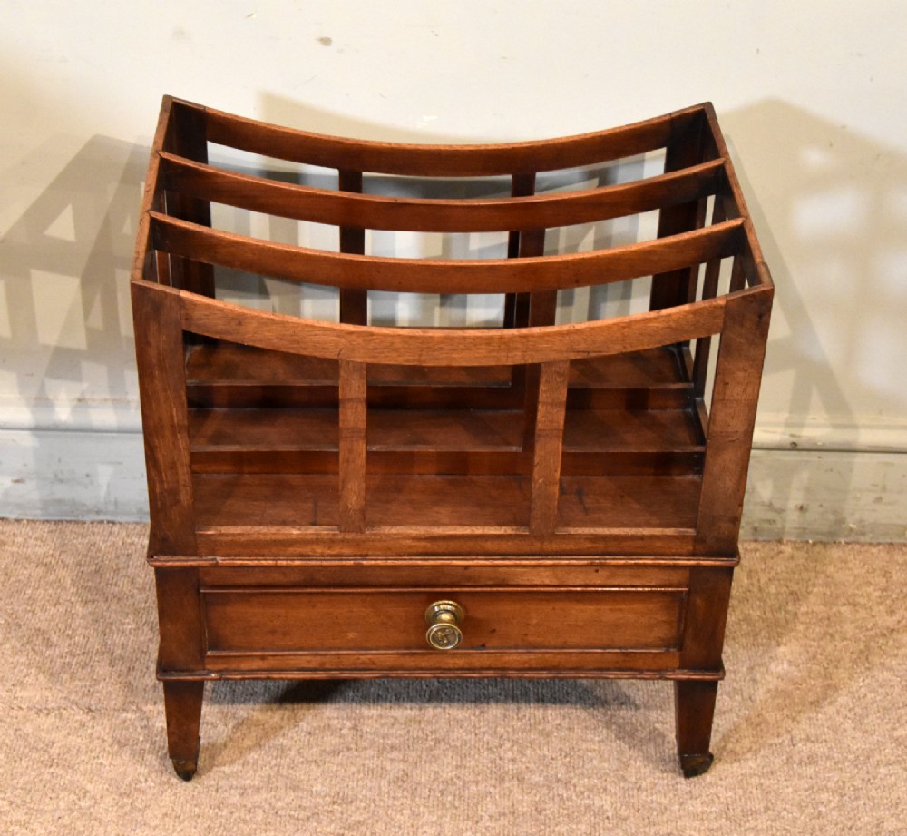A 19th-century mahogany music canterbury featuring a curved four-compartment upper section above a single drawer with a central brass knob, raised on square tapered legs with brass castors. View II