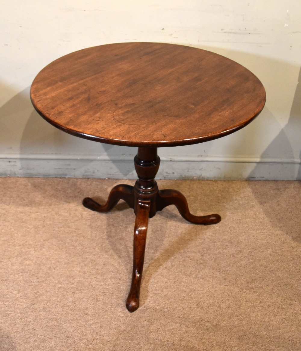 A George III mahogany tilt-top tripod table shown with its circular top tilted vertically on a turned stem and cabriole legs. View IV